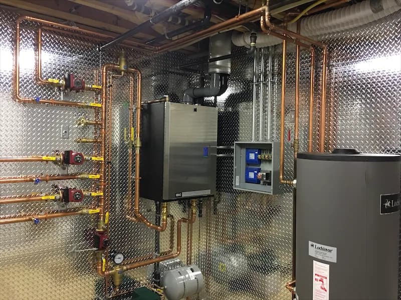Completed boiler installation with a copper manifold, zone valves, circulators and a hot water tank